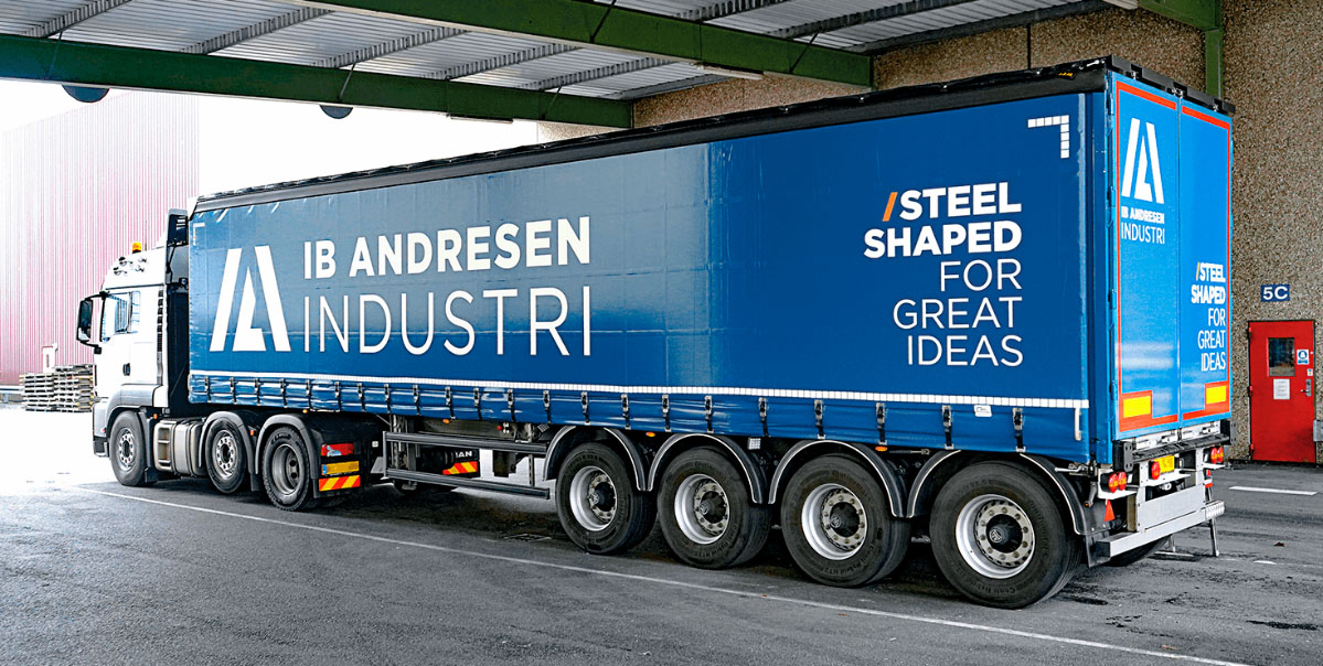 Holdende lastbil med Ib Andresen Industri logo og pay-off på gardintrailer
